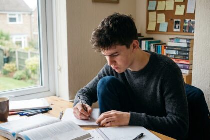Jeune étudiant concentré à son bureau dans une chambre moderne